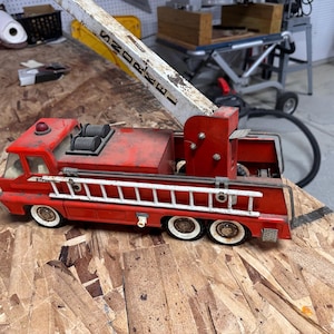 May include: Red toy fire truck with a white ladder and a working crane. The crane is labeled "Snorkel".