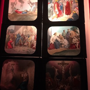 May include: A set of six vintage glass slides depicting scenes from the life of Jesus Christ. The slides are framed in black and feature colorful illustrations.
