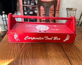May include: Red wooden carpenter tool box with a white handle and white lettering that reads "Carpenter Tool Box".