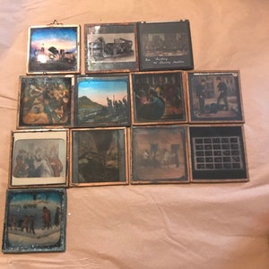 May include: A collection of 12 antique glass slides in wooden frames. The slides depict various scenes, including a city skyline, a group of people, and a landscape. The slides are in good condition and would be a great addition to any antique collection.