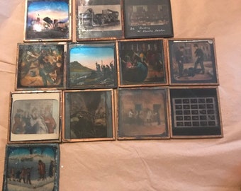 Op de afbeelding: Een verzameling van 12 antieke glazen dia's in houten frames. De dia's tonen verschillende scènes, waaronder een skyline, een groep mensen en een landschap. De dia's zijn in goede staat en zouden een geweldige aanvulling zijn op elke antieke collectie.