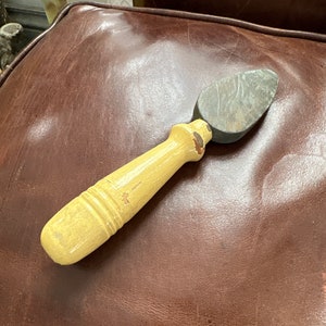 May include: A yellow wooden handled shoe shine brush with a gray stone attached to the end.