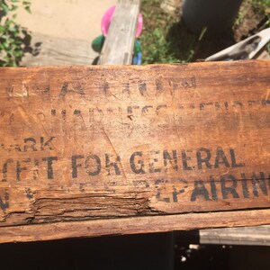 May include: Close-up of a wooden box with black text that reads "TRADE MARK" and "SUIT FIT FOR GENERAL REPAIRING."