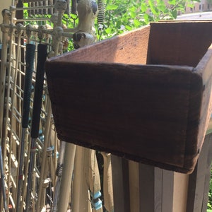 May include: A wooden box with a rustic brown finish. The box is empty and has a rectangular shape.