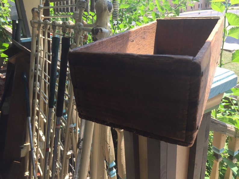 May include: A wooden box with a rustic brown finish. The box is empty and has a rectangular shape.