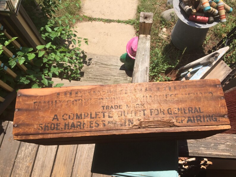 May include: A wooden box with the text "A Complete Outfit For General Shoe, Harness and Gin Repairing." The box is weathered and has a brown stain.