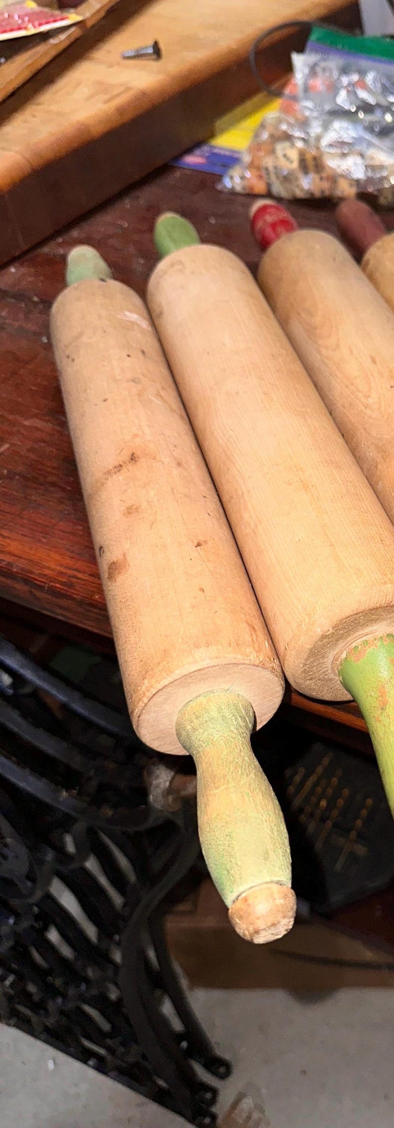 K&ouml;nnte beinhalten: Eine Sammlung von Nudelrollen aus Holz mit hellbraunen Walzen und gr&uuml;nen Griffen. Die Nudelrollen sind auf einer dunklen Holzoberfl&auml;che angeordnet und zeigen ihre nat&uuml;rliche Holzmaserung und ihren Vintage-Look.
