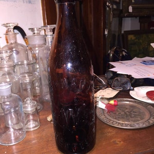May include: A dark brown glass bottle with a cork top. The bottle has embossed lettering on the front that reads "Wm. Martin & Co. Brewers,  Winnipeg".