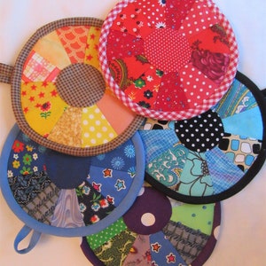 May include: Five colorful quilted pot holders with different patterns and colors. Each pot holder has a loop handle. The pot holders are made of fabric scraps and are in a variety of colors, including red, blue, green, yellow, and purple.