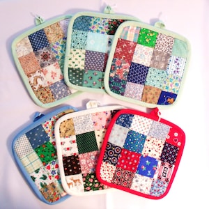 May include: A collection of six square patchwork potholders. Each potholder features a unique arrangement of small fabric squares in various floral and patterned designs. The potholders have different colored borders, including green, blue, and red, with a loop for hanging.