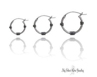 May include: Three silver hoop earrings with a twisted wire design. The earrings are shown in different sizes.