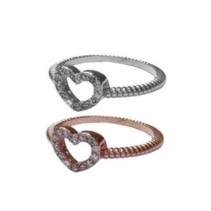 May include: Two heart-shaped rings with a twisted band. One ring is silver with a clear heart, and the other is rose gold with a clear heart.