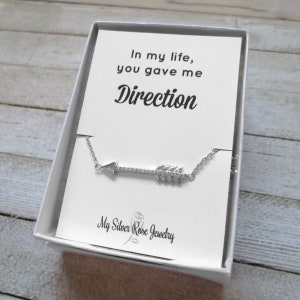 May include: A silver arrow necklace in a white gift box. The arrow pendant is detailed with small crystals. The card inside the box reads "In my life, you gave me Direction" and "My Silver Rose Jewelry".