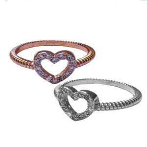 May include: Two heart-shaped rings with a clear stone border. The ring on the left is rose gold and the ring on the right is silver.