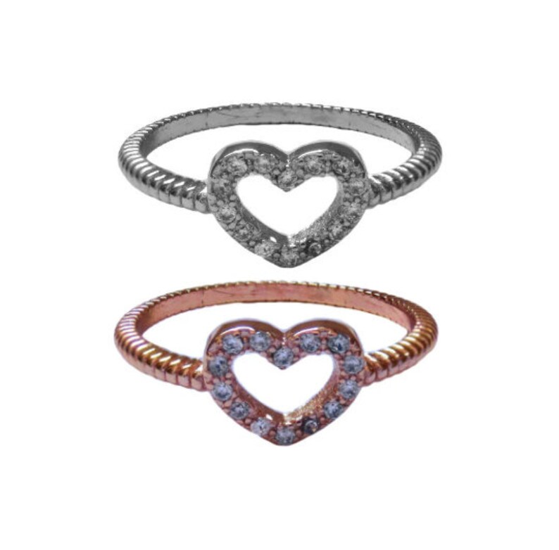 May include: Two heart-shaped rings with a pave setting of clear stones. The ring on top is silver, and the ring on the bottom is rose gold.
