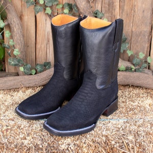 Op de afbeelding: Een paar zwarte leren cowboylaarzen met een slangenhuidpatroon. De laarzen hebben een spitse neus en een lage hak.