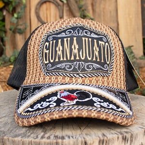 May include: A woven straw-style trucker hat with a black mesh back. The front features a black patch with the word "GUANAJUATO" in white script. Below, a black and white embroidered design includes a rooster.