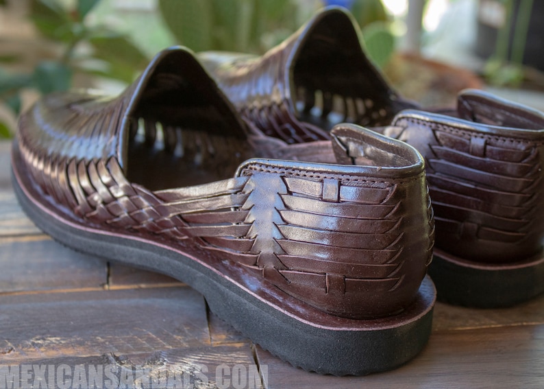 May include: A pair of brown leather sandals with a woven design. The sandals have a thick sole and are made of a soft, supple leather.