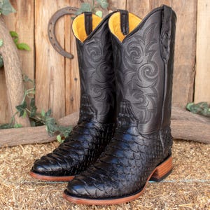 Könnte beinhalten: Schwarze Leder-Cowboystiefel mit einem gemusterten Design und einer spitzen Zehenkappe. Die Stiefel sind aus echtem Alligatorleder.