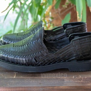 May include: Black leather sandals with a woven design and a thick black sole.