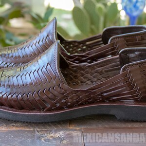 May include: A pair of brown leather sandals with a woven design. The sandals have a closed toe and a flat sole.