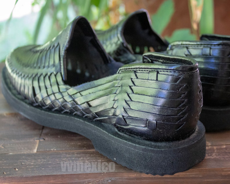 May include: A pair of black leather huarache sandals with a woven design. The sandals have a thick black sole and are made of a soft, supple leather.