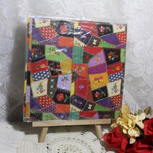 May include: A colorful patchwork design, featuring squares of various colors and floral patterns. The fabric is packaged in clear plastic and displayed on a small wooden easel. The overall theme is a vintage, handcrafted aesthetic.