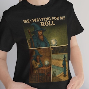 May include: Black t-shirt with a graphic of a wizard in a blue robe and hat, with the text "ME: WAITING FOR MY ROLL". The graphic is a comic strip style with the wizard in different poses.