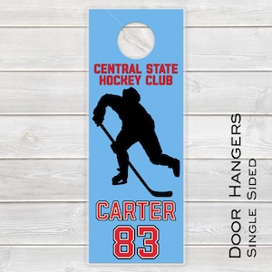 May include: A light blue door hanger with a black silhouette of a hockey player in action. The text "CENTRAL STATE HOCKEY CLUB" is in red. Below the silhouette is the name "CARTER" and the number "83" in red. The words "DOOR HANGERS SINGLE SIDED" are printed vertically.