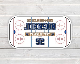 May include: A sticker featuring a hockey rink design with the text "120 GOLD 2024-2025 JOHNSON FRANKLIN FURY 92". The design includes blue, brown, and red accents on a white background.