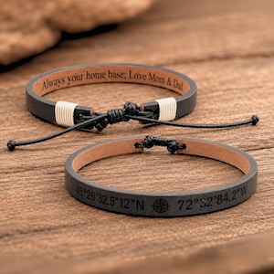 May include: Two dark gray leather bracelets with adjustable black cord closures. One bracelet features the engraved text Always your home base; Love Mom & Dad. The other bracelet displays engraved coordinates 45°26'32.5"12"N 72°32'84.2"W.