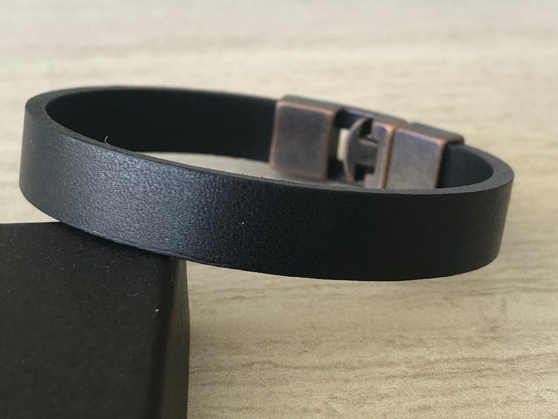 May include: A black leather bracelet with a silver and copper clasp.