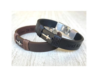 May include: Two leather bracelets, one brown and one black, each featuring a silver cross charm. The brown bracelet has the text "Matthew 28:20" and the black bracelet has the text "and Know". Both bracelets have a wrapped leather detail.