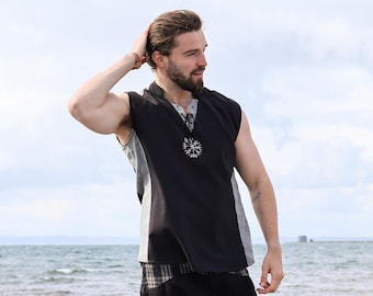 May include: A black sleeveless tunic featuring a grey side panel and a white Vegvisir symbol embroidered on the chest, paired with black trousers that have a grey plaid waistband and pocket detailing, worn as a complete outfit ensemble.