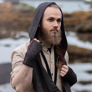 Puede incluir: Un conjunto de bufanda con capucha y guantes sin dedos en un patrón de cuadros gris oscuro con forro burdeos. El conjunto se usa sobre una camisa beige y pantalones marrones. La imagen incluye el texto "Celtic Fusion".