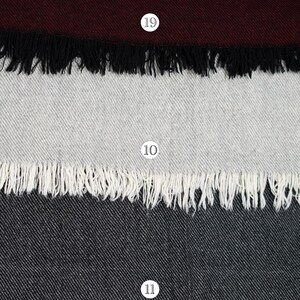 Pu&ograve; includere: Una collezione di cinque campioni di tessuto rettangolari disposti verticalmente, ognuno caratterizzato da un colore solido distinto, una trama diagonale e un bordo sfrangiato. I colori includono grigio scuro, bordeaux intenso, grigio chiaro, antracite e beige.