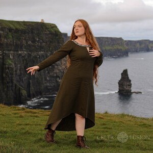 Mystical green Celtic dress with intricate Celtic embroidery, featuring a high-low skirt, buttoned sleeves, and a medieval-inspired design. A perfect choice for historical and bohemian fashion lovers.