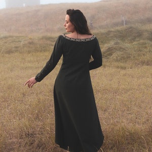 Back view of green Celtic dress with long sleeves and flowing silhouette, an alternative wedding guest dress with high low skirt and folklore styling.