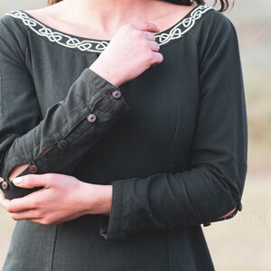 Mystical green Celtic dress with intricate Celtic embroidery, featuring a high-low skirt, buttoned sleeves, and a medieval-inspired design. A perfect choice for historical and bohemian fashion lovers.