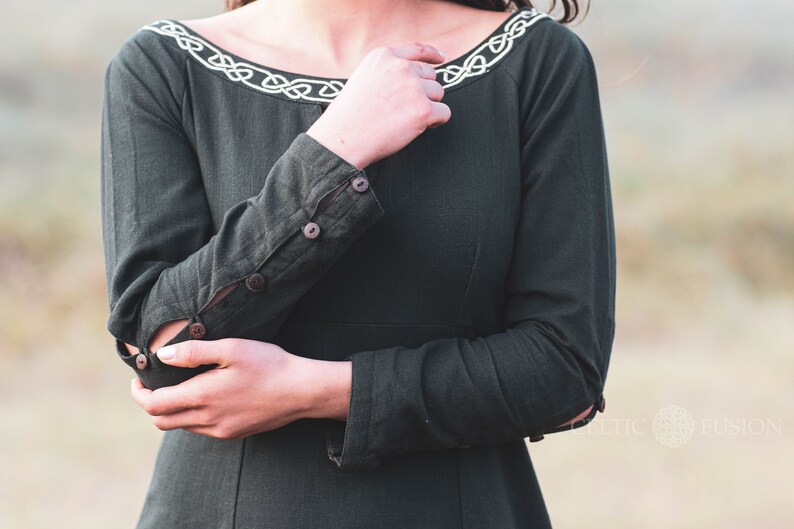 Mystical green Celtic dress with intricate Celtic embroidery, featuring a high-low skirt, buttoned sleeves, and a medieval-inspired design. A perfect choice for historical and bohemian fashion lovers.
