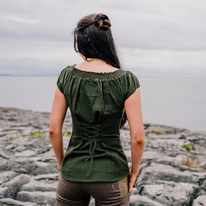 Green corset top made from 100% cotton featuring lace trim running along the front, a corset tie back, bunched sleeves, and an elasticated collar with a fairycore clothing style.