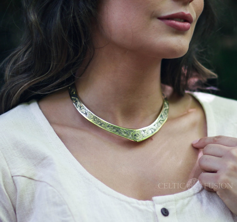 May include: A silver-toned necklace with an intricate Celtic knot design. The necklace is curved and has a delicate, feminine look.