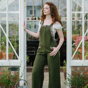 Adjustable Green Dungarees styled in a greenhouse doorway with wide leg fit and checked trim details