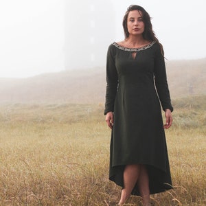 Mystical green Celtic dress with intricate Celtic embroidery, featuring a high-low skirt, buttoned sleeves, and a medieval-inspired design. A perfect choice for historical and bohemian fashion lovers.