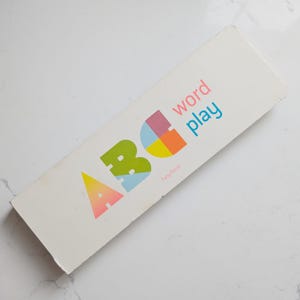 May include: A rectangular white box featuring the colourful text ABC word play. The letter A is a yellow and pink gradient, B is green, and C is a segmented circle of pink, blue, yellow, and orange. The name Fany Perret is printed in small pink text.