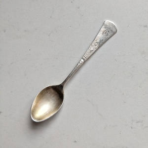 Peut inclure: Une cuillère en argent avec un bol ovale et un manche décoratif. La poignée présente des motifs floraux et géométriques gravés, et une lettre "G" est gravée à l'extrémité de la cuillère. La cuillère est probablement vintage ou antique.