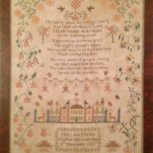 May include: A framed antique sampler with a detailed cross-stitch design. The artwork features a poem, floral borders, and a central illustration of a building and deer. The text reads "My hiding place, my refuge-tow't..." and is signed "Mary Ann Mitton, 5th November 1832."