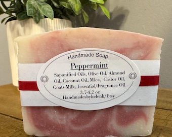May include: A rectangular bar of handmade peppermint soap with a white and pink marbled pattern. A white oval label features the text: Handmade Soap Peppermint, Saponified Oils, Olive Oil, Almond Oil, Coconut Oil, Mica, Castor Oil, Goats Milk, Essential/Fragrance Oil, 3.7-4.2 oz, Handmadesbyhelenk/Etsy.