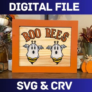 May include: A wooden sign with an orange frame, featuring the text "BOO BEES" in black and white lettering. Two cartoon ghosts with bee wings are depicted on the sign.