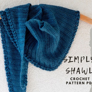 May include: A teal blue crochet shawl hanging on a wooden hanger. The shawl has a textured edge and is made with a simple stitch pattern. The text "SIMPLY SHAWL CROCHET PATTERN PDF" is written in black on a white background.
